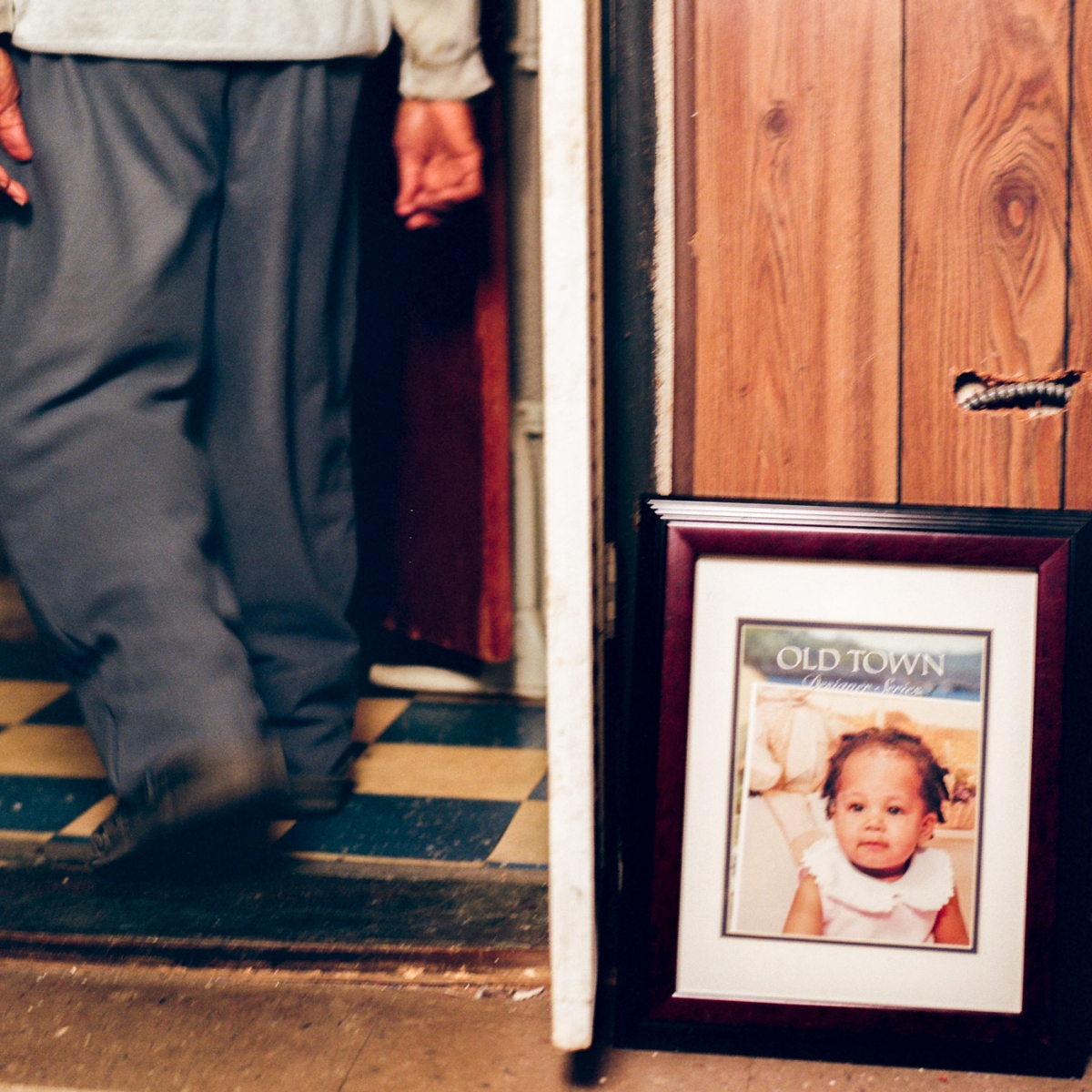 Man's legs in a doorway next to a framed photo of a child